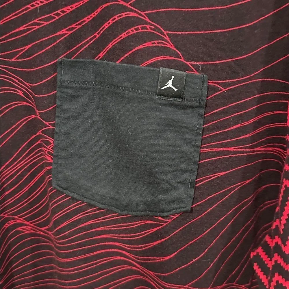 Jordan men's tee in red and black with a unique all-over pattern and a pocket.